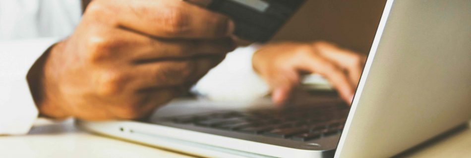 Person am Laptop mit Bankunterlagen und Polizeivorladung – Symbolbild für Geldwäscherei-Ermittlungen gegen Opfer eines Online-Betrugs.